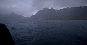 Movie still from “Into the Inferno” (2016), directed by Werner Herzog – A body of water with mountains in the background; Extreme Wide shot, High angle