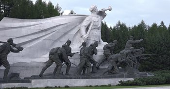 Movie still from “Into the Inferno” (2016), directed by Werner Herzog – A large statue of a man holding a baseball bat; Extreme Wide shot, Low angle