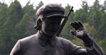 Movie still from “Into the Inferno” (2016), directed by Werner Herzog – A statue of a man holding a rifle; Extreme Close Up shot, Low angle