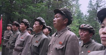 Movie still from “Into the Inferno” (2016), directed by Werner Herzog – A group of men in military uniforms standing next to each other; Medium shot, Low angle