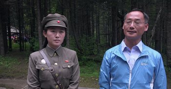 Movie still from “Into the Inferno” (2016), directed by Werner Herzog – A man and a woman dressed in military uniforms; Medium shot, Over the shoulder angle
