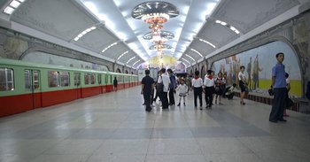 Movie still from “Into the Inferno” (2016), directed by Werner Herzog – A group of people standing in a train station; Wide shot, High angle
