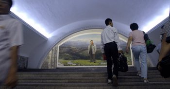 Movie still from “Into the Inferno” (2016), directed by Werner Herzog – A man walking up some steps in a tunnel; Wide shot, Low angle
