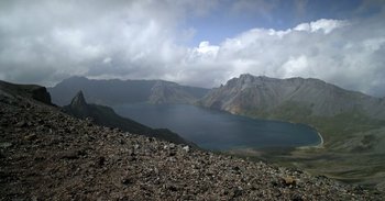 Movie still from “Into the Inferno” (2016), directed by Werner Herzog – A view of a mountain lake from a mountain top; Extreme Wide shot, High angle
