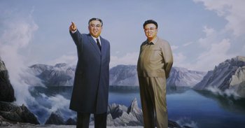 Movie still from “Into the Inferno” (2016), directed by Werner Herzog – Two men standing next to each other in front of mountains; Medium shot, Low angle