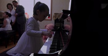 Movie still from “Into the Inferno” (2016), directed by Werner Herzog – A little girl is playing the piano in her room; Close Up shot, High angle