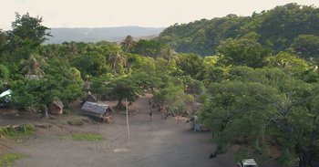 Movie still from “Into the Inferno” (2016), directed by Werner Herzog – An aerial view of people walking in a dirt field; Extreme Wide shot, High angle