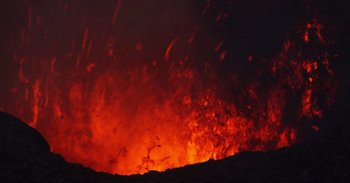 Movie still from “Into the Inferno” (2016), directed by Werner Herzog – A large lava eruption in the night sky; Extreme Wide shot, High angle