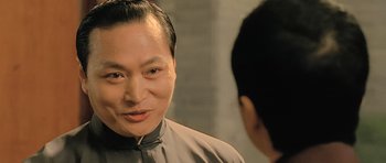 Movie still from “Ip Man” (2008), directed by Wilson Yip – A man in a gray shirt is talking to another man; Close Up shot, Over the shoulder angle
