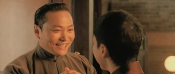 Movie still from “Ip Man” (2008), directed by Wilson Yip – A man smiling at another man in a brown suit; Close Up shot, Over the shoulder angle
