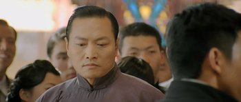 Movie still from “Ip Man” (2008), directed by Wilson Yip – A person wearing a suit and tie; Close Up shot, Low angle