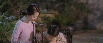 Movie still from “Ip Man” (2008), directed by Wilson Yip – A woman and a child are painting on a table; Medium shot, High angle