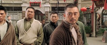 Movie still from “Ip Man” (2008), directed by Wilson Yip – A group of men standing next to each other in front of a building; Medium shot, Low angle