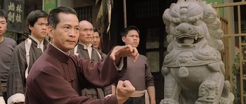 Movie still from “Ip Man” (2008), directed by Wilson Yip – A group of men standing next to each other in front of a statue; Medium shot, Low angle