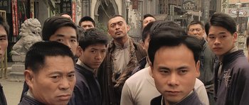 Movie still from “Ip Man” (2008), directed by Wilson Yip – A group of men standing next to each other in front of a building; Medium shot, Low angle