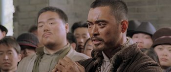 Movie still from “Ip Man” (2008), directed by Wilson Yip – A group of men standing next to each other in a room; Close Up shot, Over the shoulder angle