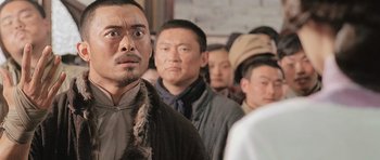 Movie still from “Ip Man” (2008), directed by Wilson Yip – A group of men standing next to each other in a room; Close Up shot, Over the shoulder angle