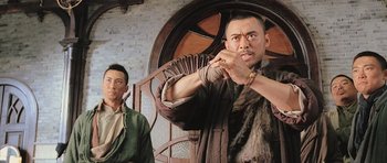 Movie still from “Ip Man” (2008), directed by Wilson Yip – A man with a knife in his mouth and another man with a knife in his other hand; Medium shot, Low angle