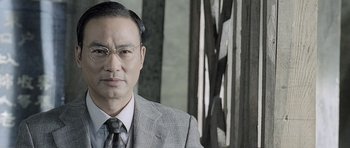 Movie still from “Ip Man” (2008), directed by Wilson Yip – A man in a suit and tie wearing glasses; Close Up shot, Low angle