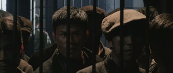 Movie still from “Ip Man” (2008), directed by Wilson Yip – A group of men standing next to each other in front of a fence; Medium shot, High angle