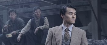 Movie still from “Ip Man” (2008), directed by Wilson Yip – A man in a suit standing next to another man in a suit; Medium shot, Low angle