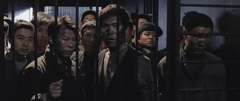 Movie still from “Ip Man” (2008), directed by Wilson Yip – A group of men standing next to each other in front of a fence; Medium shot, Low angle