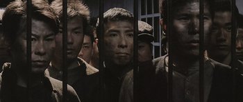 Movie still from “Ip Man” (2008), directed by Wilson Yip – A group of men standing next to each other in front of a fence; Medium shot, High angle