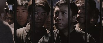 Movie still from “Ip Man” (2008), directed by Wilson Yip – A group of men standing next to each other behind bars; Medium shot, High angle