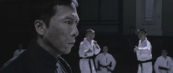Movie still from “Ip Man” (2008), directed by Wilson Yip – A man standing in front of two other men in black and white uniforms; Close Up shot, Low angle