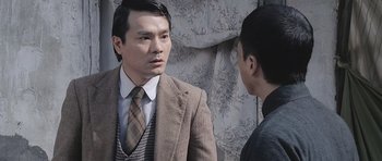 Movie still from “Ip Man” (2008), directed by Wilson Yip – A man wearing a suit and tie talking to another man; Close Up shot, Over the shoulder angle