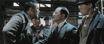 Movie still from “Ip Man” (2008), directed by Wilson Yip – A group of men standing next to each other in a room; Medium shot, Over the shoulder angle