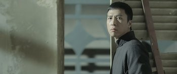 Movie still from “Ip Man” (2008), directed by Wilson Yip – A man standing next to a wall looking at the camera; Close Up shot, Low angle
