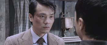 Movie still from “Ip Man” (2008), directed by Wilson Yip – A person wearing a suit and tie; Close Up shot, Over the shoulder angle