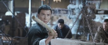 Movie still from “Ip Man” (2008), directed by Wilson Yip – A man holding a baseball bat while standing next to another man; Medium shot, Low angle