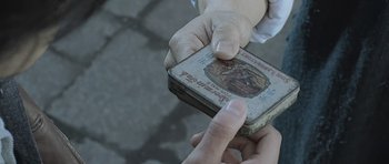 A person is holding an old tin box in their hand