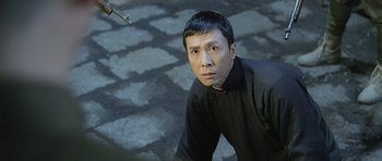 Movie still from “Ip Man” (2008), directed by Wilson Yip – A man in a black shirt and black shirt standing on the ground; Close Up shot, High angle
