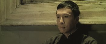 Movie still from “Ip Man” (2008), directed by Wilson Yip – A man in a black shirt is looking at the camera; Close Up shot, High angle