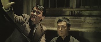 Movie still from “Ip Man” (2008), directed by Wilson Yip – Two asian men sitting next to each other; Medium shot, Low angle