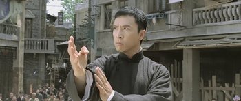 Movie still from “Ip Man” (2008), directed by Wilson Yip – A man in a black shirt clapping his hands; Medium shot, Low angle