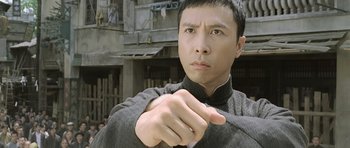 Movie still from “Ip Man” (2008), directed by Wilson Yip – A man in a black shirt is pointing his finger at the camera; Close Up shot, Low angle
