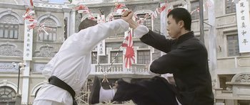 Two men holding hands in front of a building