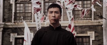 Movie still from “Ip Man 2” (2010), directed by Wilson Yip – A man standing in front of a bunch of flags; Close Up shot, Low angle