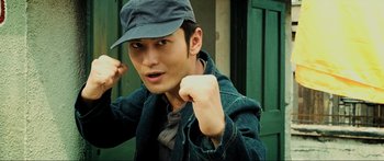Movie still from “Ip Man 2” (2010), directed by Wilson Yip – A young man wearing a hat and a denim jacket; Close Up shot, Low angle