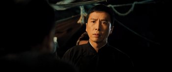 Movie still from “Ip Man 2” (2010), directed by Wilson Yip – A man in a black shirt is looking at the camera; Close Up shot, Over the shoulder angle