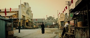 Movie still from “Ip Man 2” (2010), directed by Wilson Yip – A person walking on a street near some buildings; Extreme Wide shot, Low angle