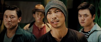 Movie still from “Ip Man 2” (2010), directed by Wilson Yip – A man wearing a hat and a black t - shirt; Close Up shot, Over the shoulder angle