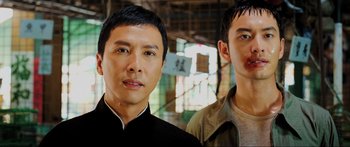Movie still from “Ip Man 2” (2010), directed by Wilson Yip – Two men standing next to each other in front of a building; Close Up shot, Low angle