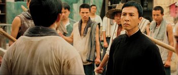 Movie still from “Ip Man 2” (2010), directed by Wilson Yip – A group of men standing next to each other; Medium shot, Over the shoulder angle