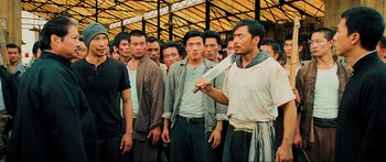 Movie still from “Ip Man 2” (2010), directed by Wilson Yip – A group of men standing in front of each other holding a knife; Medium shot, High angle