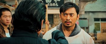 Movie still from “Ip Man 2” (2010), directed by Wilson Yip – A man looking at another man in front of a building; Close Up shot, Over the shoulder angle